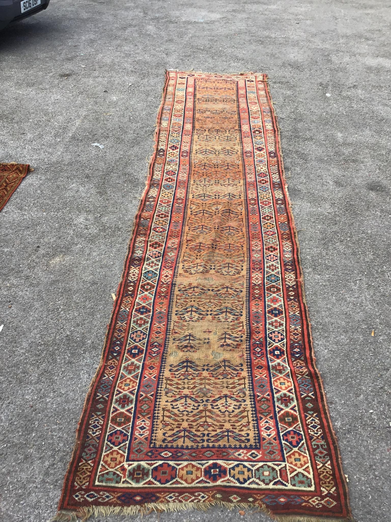 An antique Caucasian brick red ground runner, 410 x 100cm